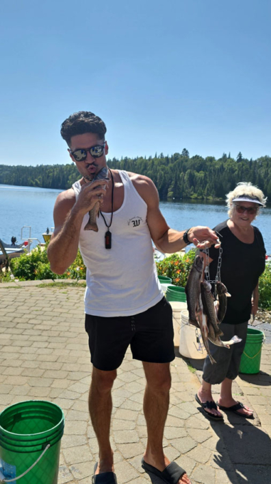 Jeune homme embrassant un poisson à la pourvoirie Au Pays de Réal Massé
