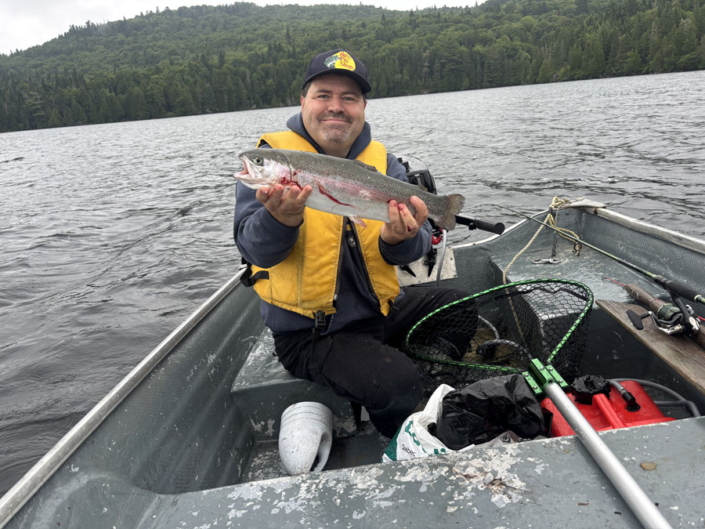 Homme en chaloupe avec une truite à la pourvoirie au Pays de Réal Massé